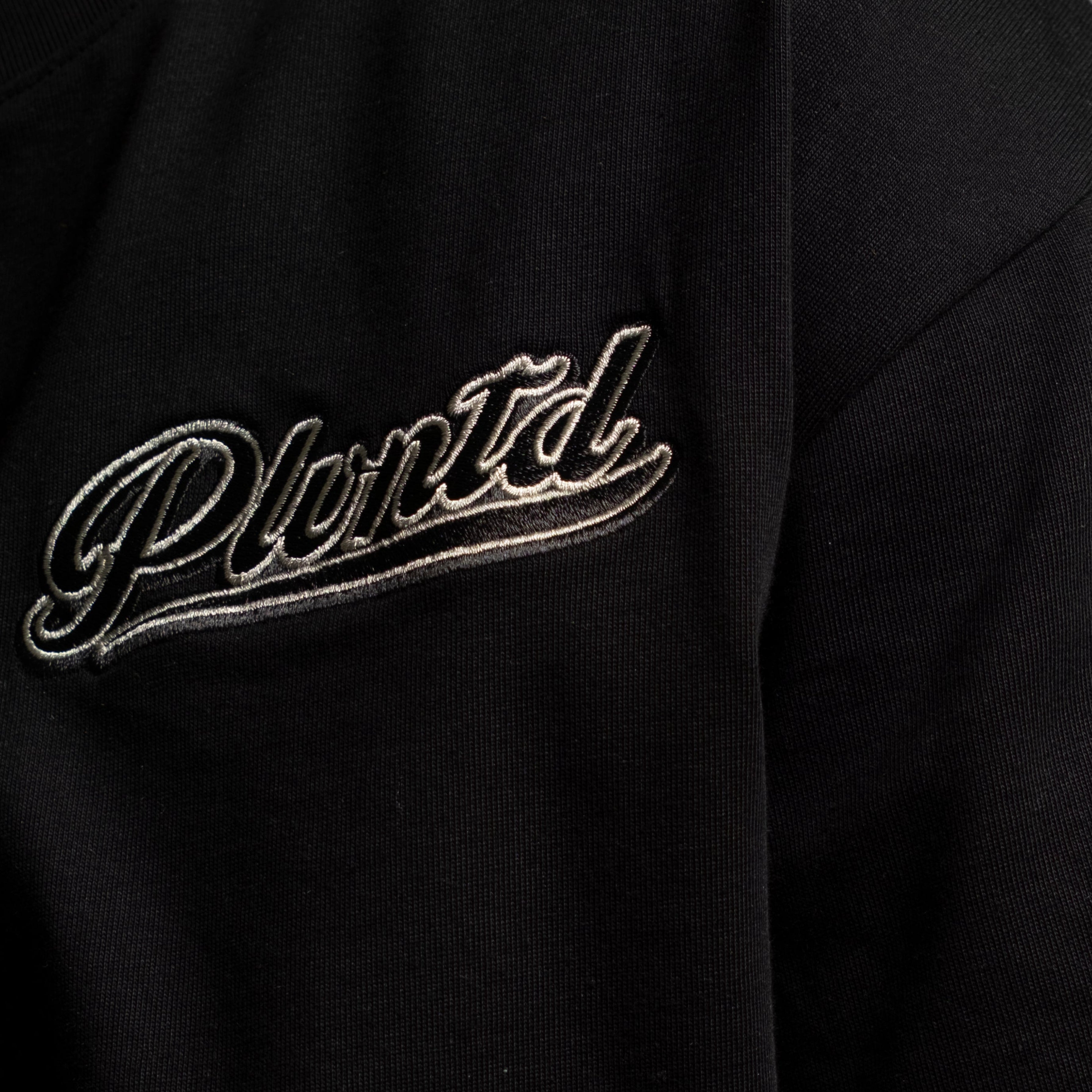 Black t-shirt with PLVNTD logo on a gray background